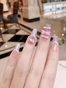 Detailed view of pink cat eye coffin nails with 3D crystal hearts and bows