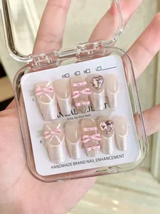 Detail of handmade press-on nails featuring 3D pink bows, pearls and crystal rhinestones