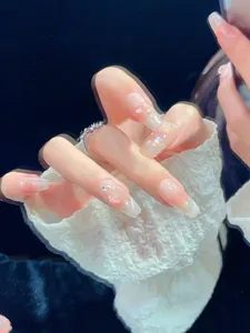Detail of almond-shaped press-on nails with pink gradient, pearls, and crystals