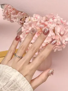 Detail of pink press-on nails with 3D floral accents and shimmering pearl decorations