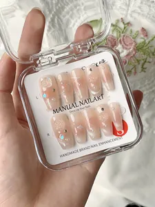 Detail of handmade press-on nails with 3D roses, pearls and rhinestones in a clear box