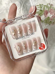 Makroansicht handgefertigter Kunstnägel mit Goldfolie und Muschelflocken in einer Box