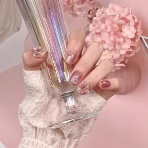 Pink cat eye handmade press-on nails with 3D floral and pearl accents on hand
