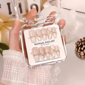Handmade soft pink marble press-on nails with gold leaf and pearl accents in packaging