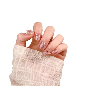 Pink cat eye press-on nails with 3D butterflies and pearl accents on a white background