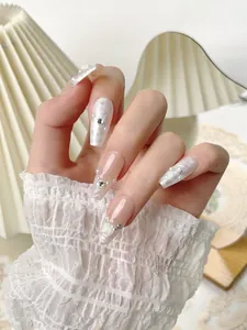 Vue détaillée de faux ongles longs avec roses 3D blanches, perles et strass brillants