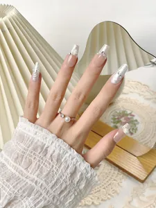 Détail de faux ongles faits main avec motifs marbrés, roses blanches et perles
