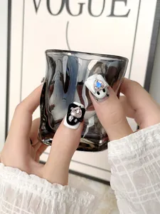 Dettaglio di unghie finte artigianali con strass a cuore e toni bicolore bianco e nero