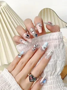 Detail view of pink and blue handmade press-on nails with 3D crystal charms and glitter