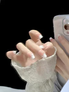 Close-up of handmade French gradient press-on nails with white tips and glitter accents