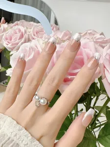 Detail of nude blush press-on nails with French tips and double pearl ring ornament