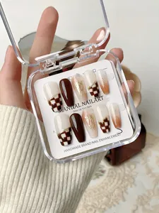 Detail of handmade amber checkerboard press-on nails with gold foil in a storage box