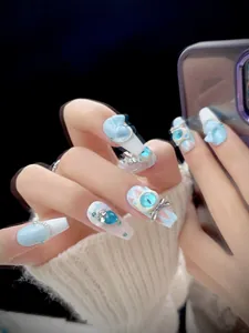 Detail of blue and white coffin press-on nails with 3D cat charms and rhinestones