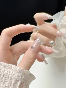 Detail of long coffin cat-eye press-on nails with sparkling rhinestones and glitter