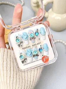 Close-up of handmade 3D light blue coffin press-on nails with bows and heart gems