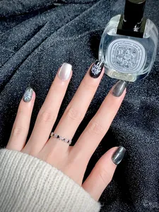 Détail de faux ongles œil de chat argenté et fleurs noires avec une bague cœur argentée
