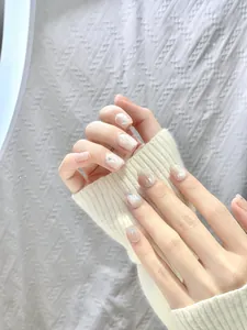 Detail of short square press-on nails with nude shimmer and rainbow butterfly sequins