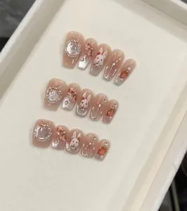 Detail view of 3D bunny and strawberry charms on pink ombre press-on nails with pearls