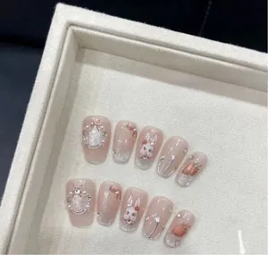 Close-up of handmade press-on nails featuring 3D rabbits, silver glitter, and heart details