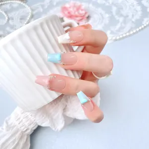 Handmade press-on nails with blue and pink French tips, heart charms, and pearls