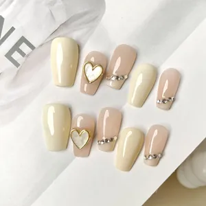 Faux ongles faits main forme cercueil blanc crème et rose nude avec cœurs dorés et strass brillants