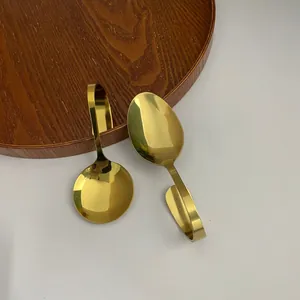 Makro-Detail goldener Edelstahllöffel mit gebogenem Griff und poliertem Spiegelglanz