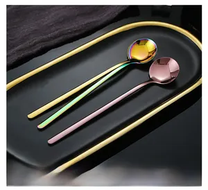 Detail of rose gold and rainbow stainless steel spoons on a black tray for coffee