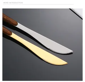 Makroaufnahme von Silber- und Gold-Steakmessern mit Wellenschliff und Griffen in Holzoptik
