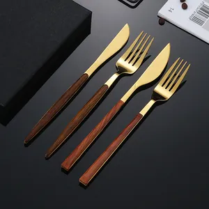 Goldenes Besteckset aus Edelstahl mit Holzmaserung auf dunkler reflektierender Fläche