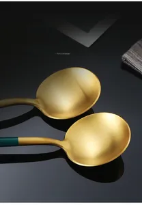 Dettaglio di cucchiai dorati opachi con manici verde scuro e texture in metallo spazzolato