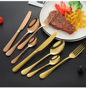 Polished rose gold and gold stainless steel cutlery set displayed with steak and pasta