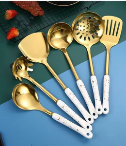 Close-up of gold stainless steel utensils with white marble ceramic handles in a set