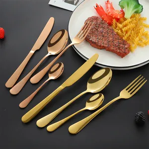 Mirror polished stainless steel cutlery set in rose gold and gold displayed on a dark table