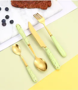 Detail of 4-piece gold cutlery set with green marble handles on a minimalist background