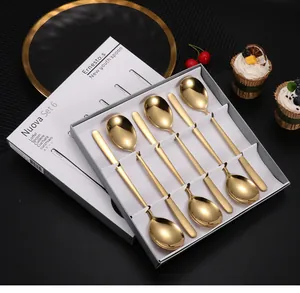 Détail de six cuillères à dessert dorées en acier inoxydable dans un coffret cadeau gris