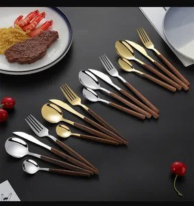Detail of 24-piece stainless steel cutlery set with wood grain handles on dark surface