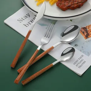 24-piece stainless steel cutlery set with wood-grain handles on a dining table