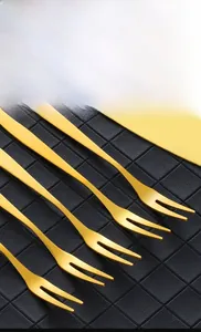 Detailed view of 5-piece gold stainless steel dessert forks on black textured background