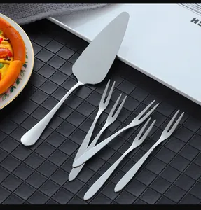 Close-up of stainless steel cake server and five dessert forks on a black background