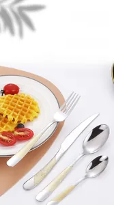 Detail of stainless steel cutlery set with golden diamond textured handles on a placemat