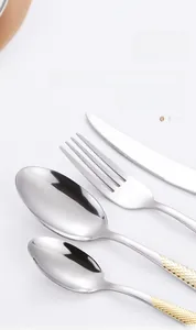 Detail of stainless steel cutlery set with mirror finish and golden diamond pattern handles