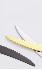 Macro detail of sharp serrated stainless steel knife blades in gold, black, and silver