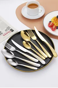 Close-up of golden and silver cutlery with textured diamond grid handles on a plate