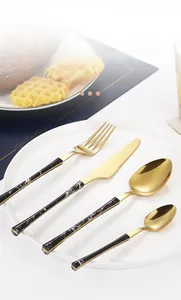 Close-up of golden stainless steel cutlery set with black marble texture handles