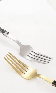 Detailed view of polished stainless steel fork teeth with smooth edges and marble handle