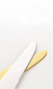 Detailed macro view of sharp serrated edges on silver and gold stainless steel steak knives