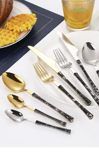 Close-up of stainless steel cutlery with marble handles on a blue placemat