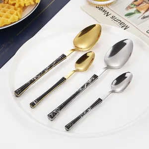 Modern marble handle stainless steel cutlery set with gold and silver spoons on a plate