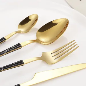 4-piece gold stainless steel cutlery set with marble textured handles on a white plate