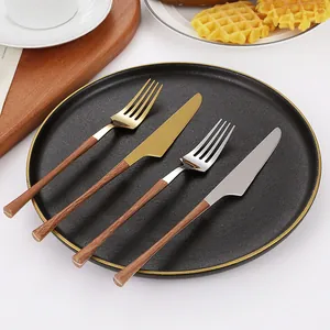 Creative 430 stainless steel cutlery set with wood grain handle on a dinner plate